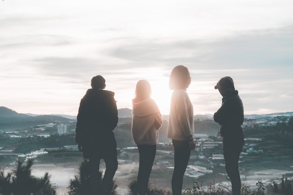 Four People Standing on Top of Hill during Sunset