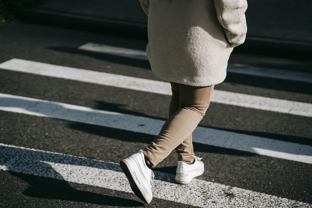 Crop faceless woman walking on zebra