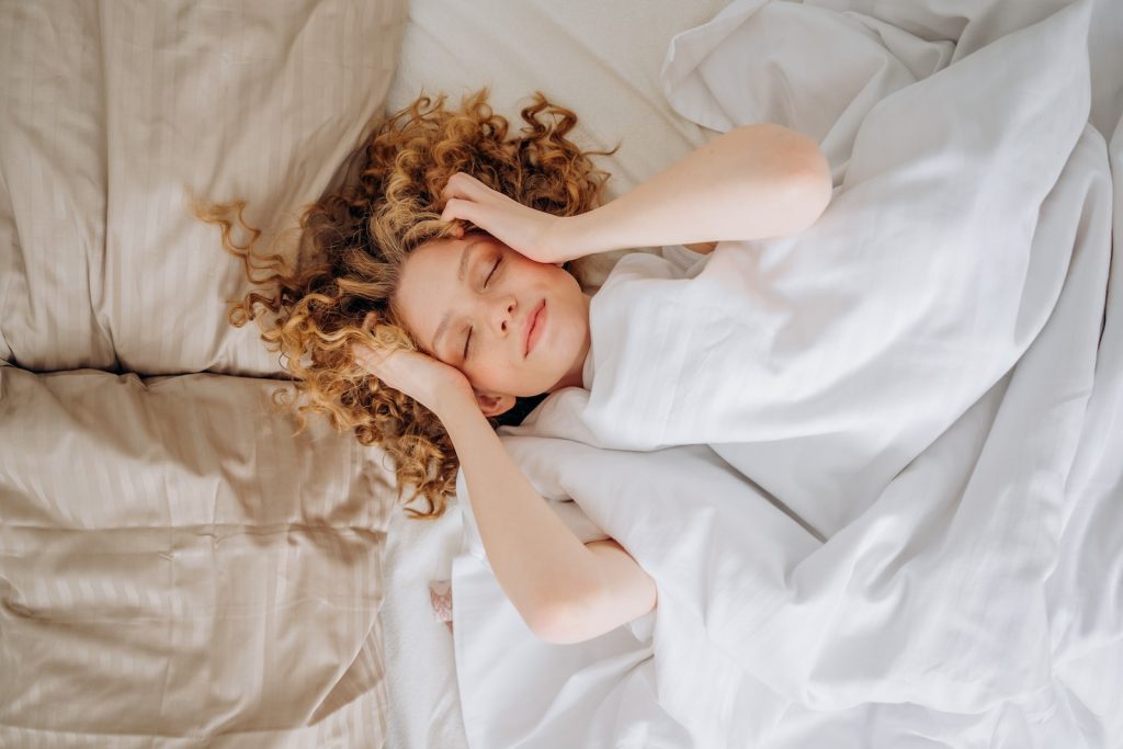 Woman Lying on Bed Covered with White Blanket