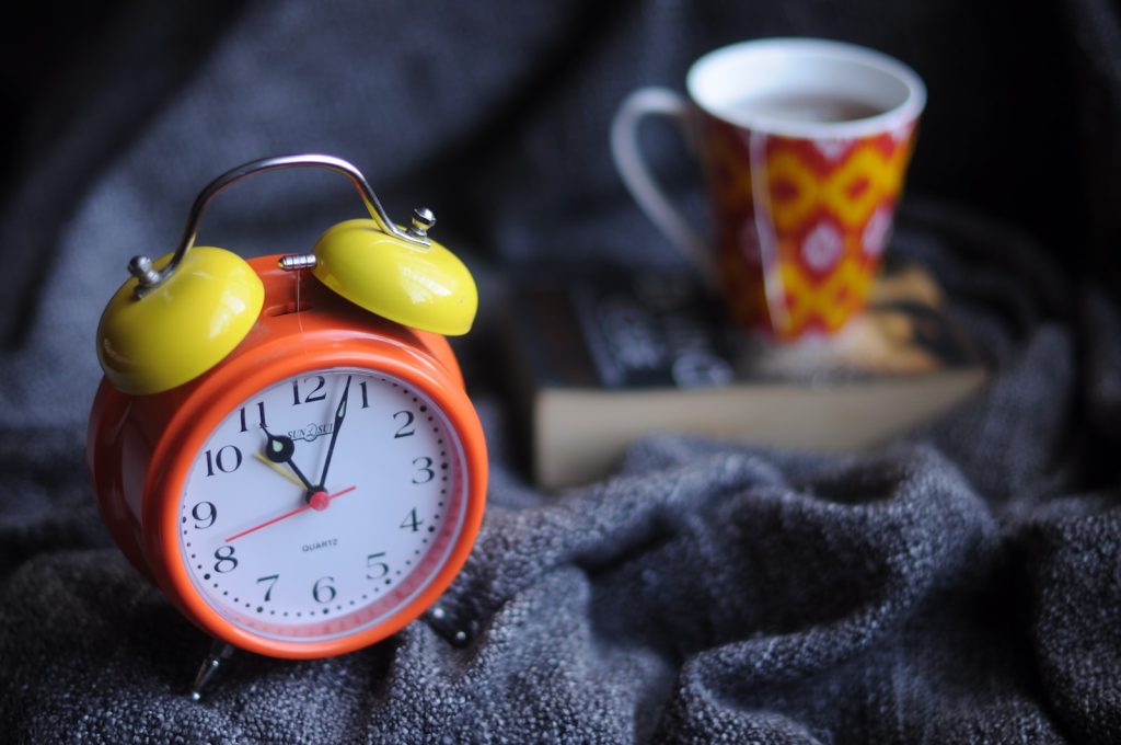 orange and yellow analog alarm clock at 11:03