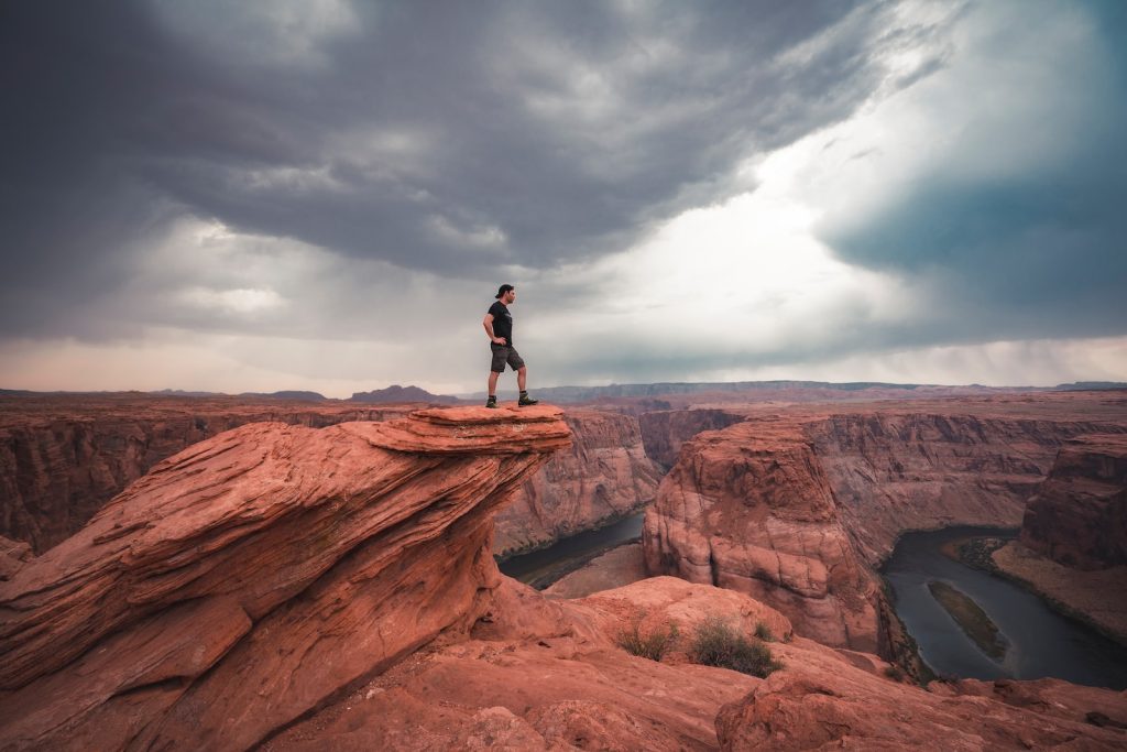 man standing on top of horseshoe bend at Arizona