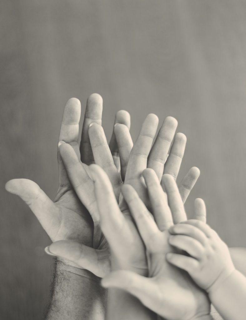 grayscale photo of family's hands