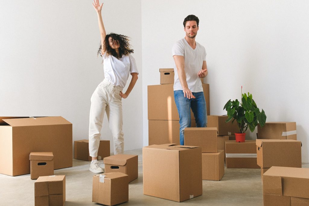 Joyful young couple dancing after moving in new purchased apartment