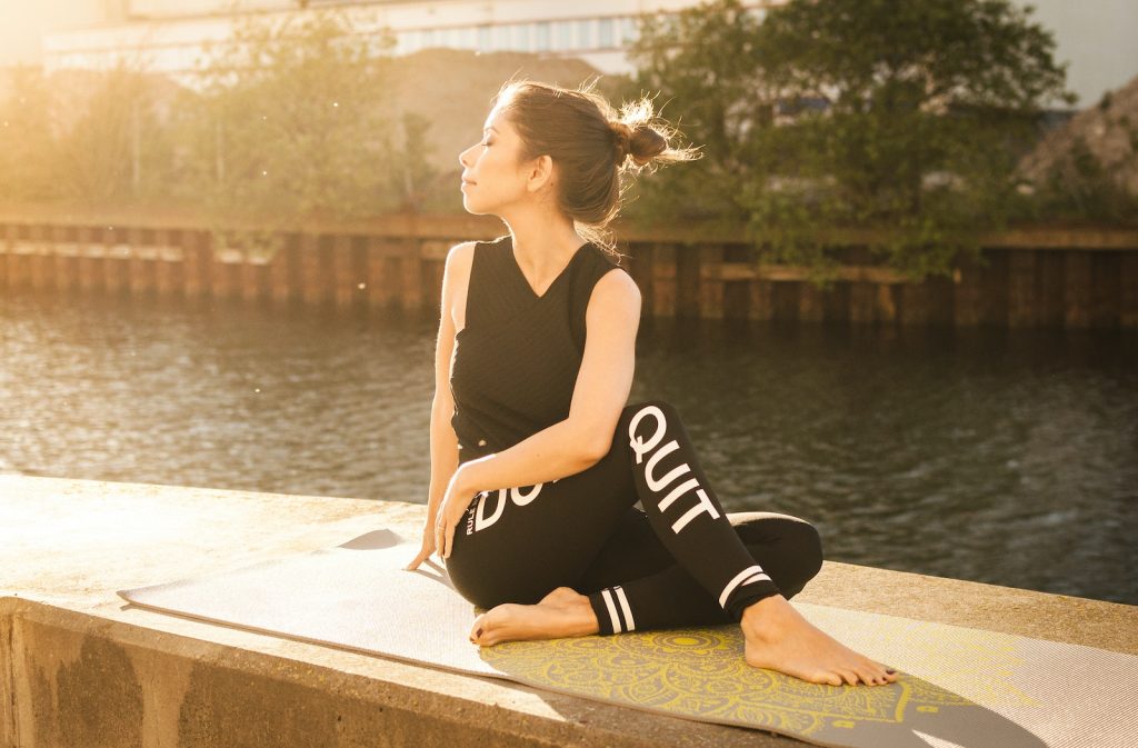 Woman Wearing Black Fitness Outfit Performs Yoga Near Body of Water