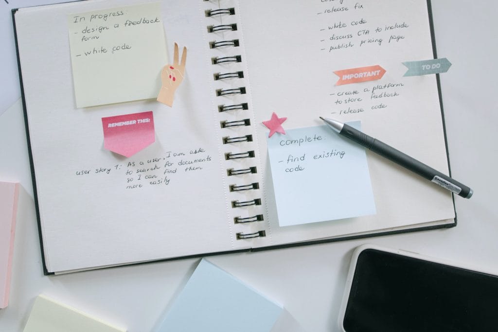 High-Angle Shot of a Notebook and a Pen Beside a Mobile Phone