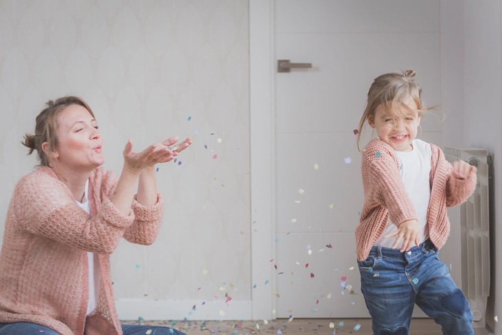 woman and child wearing beige sweater playing with confetti