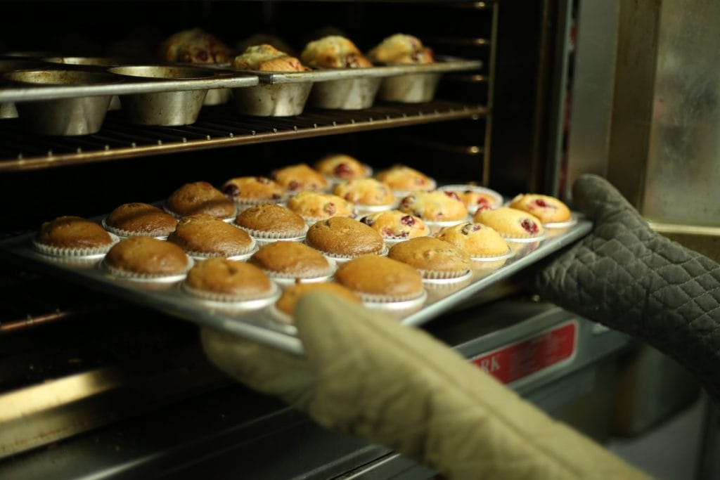 person holds tray of muffins on tray