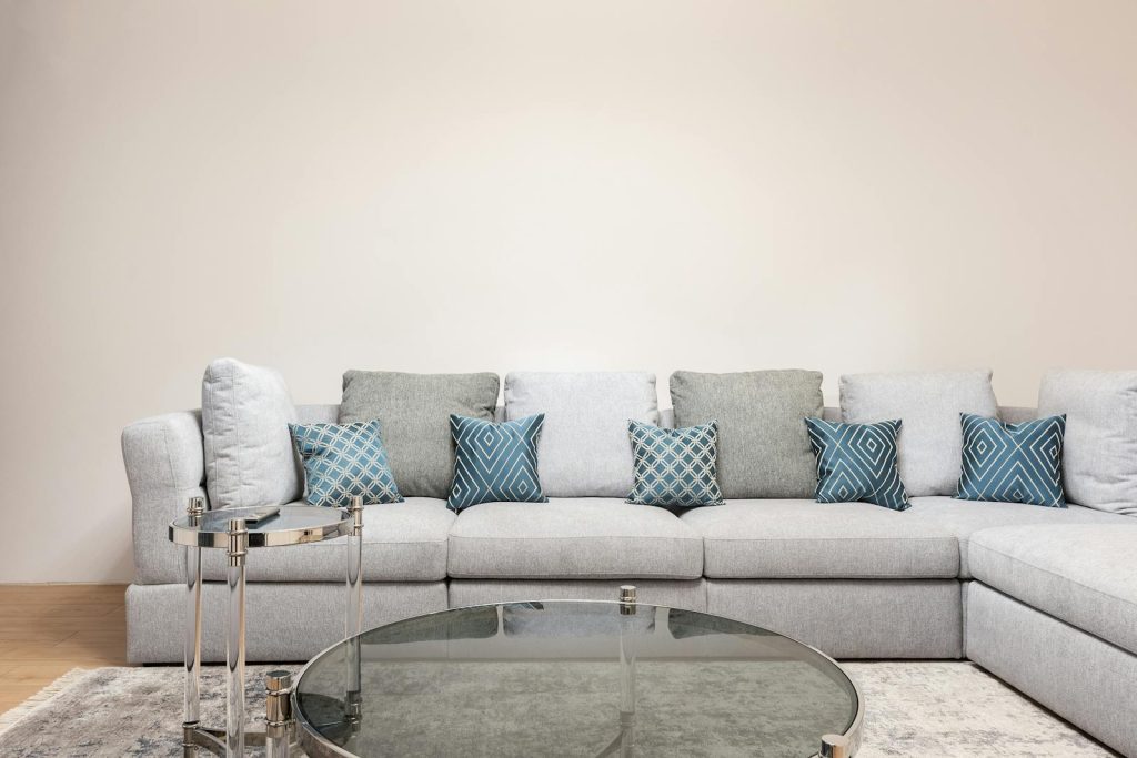 Modern room interior with decorative cushions on couch against round shaped tables on carpet at home