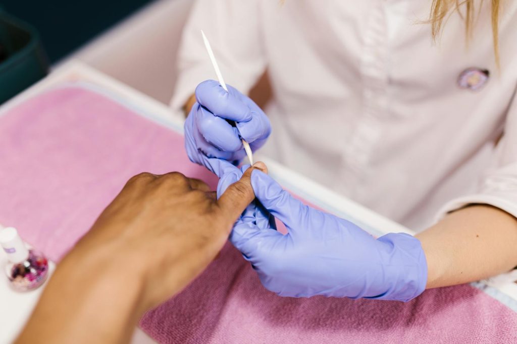 Hands Pushing Nail Cuticle of Clients Finger