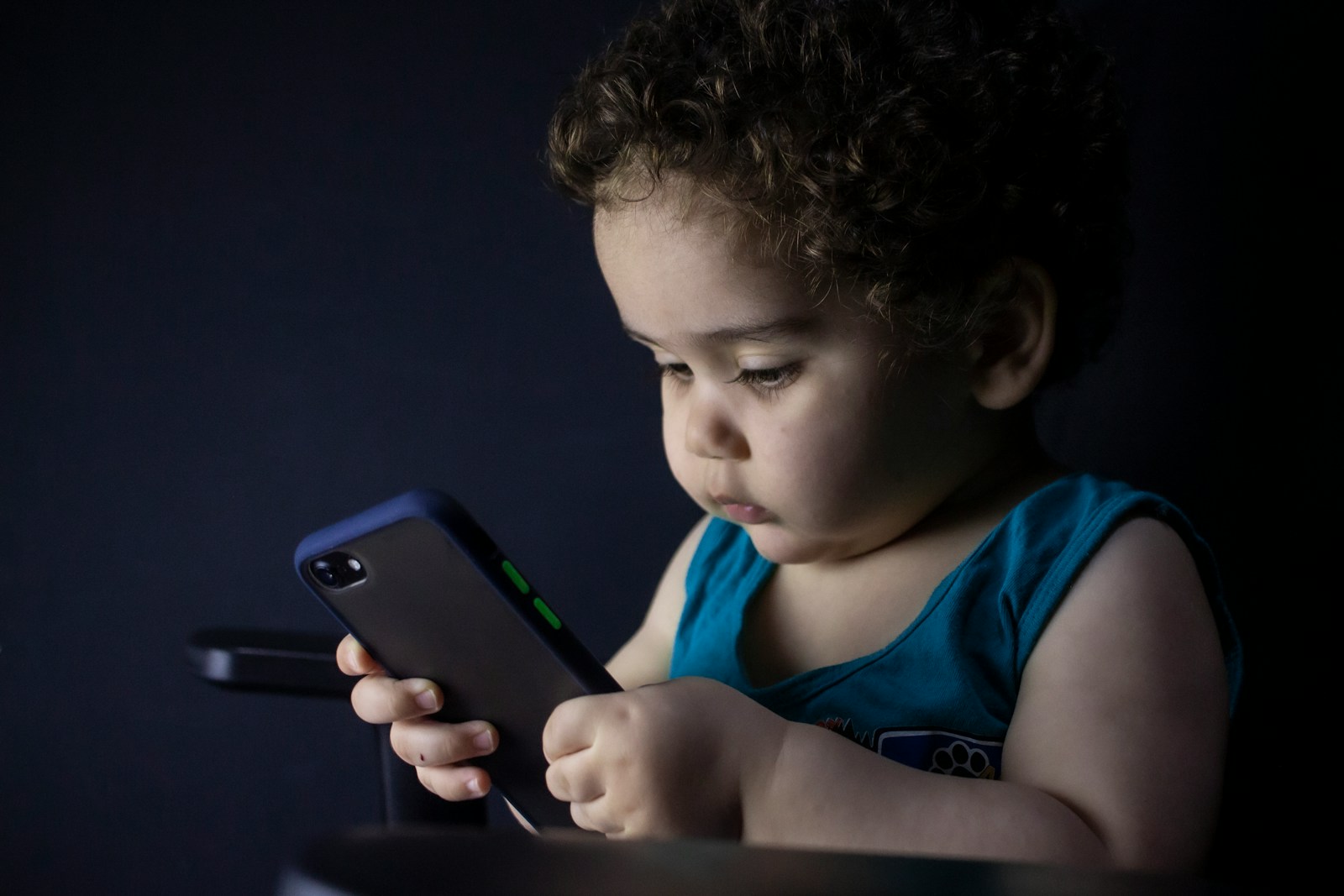 boy in blue tank top holding black iphone 5